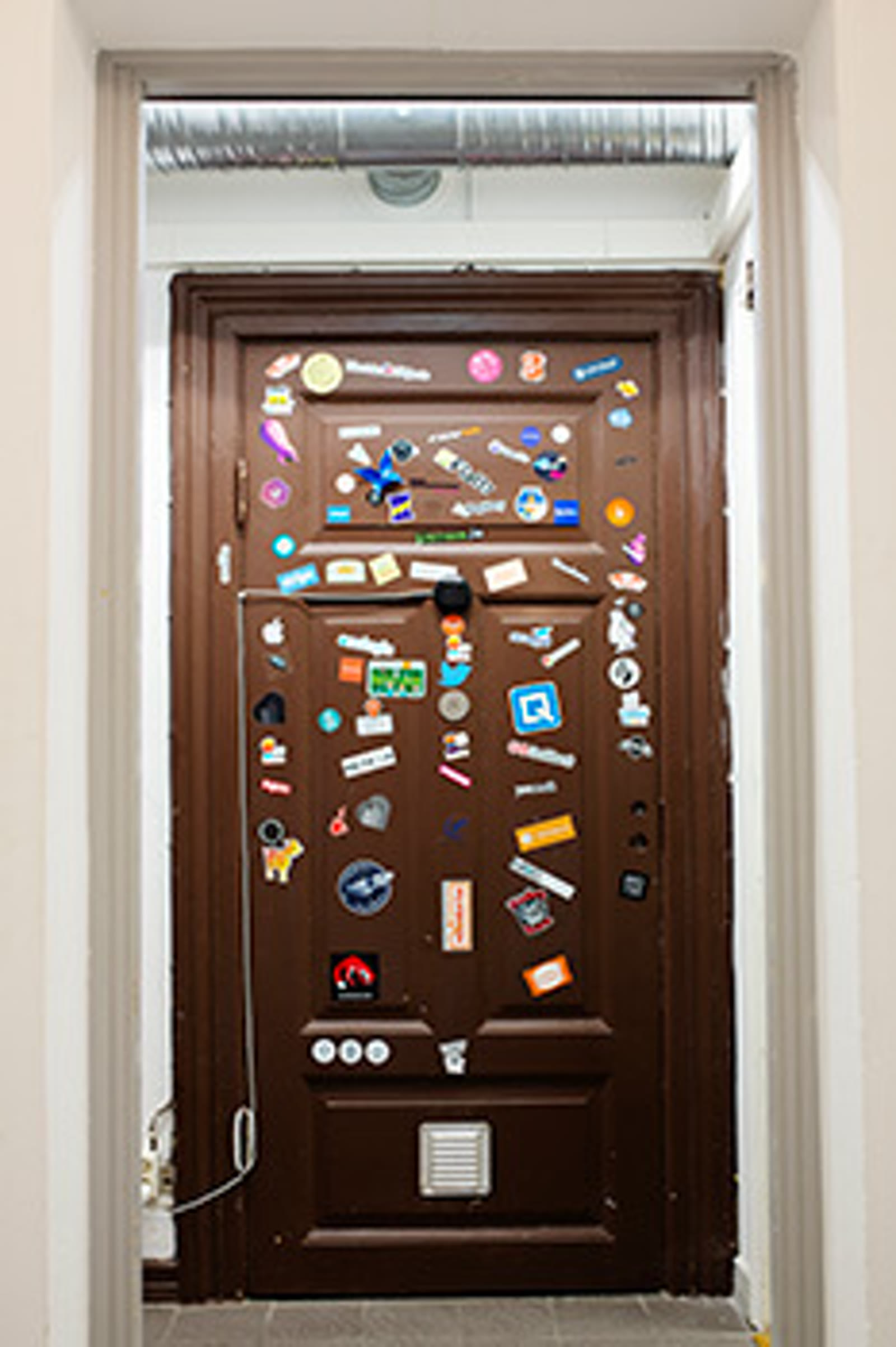 The famous brown door at The Ground, Bredgatan 4, Malmö — covered with stickers left by every founder who has built and graduated a company from this coworking space
